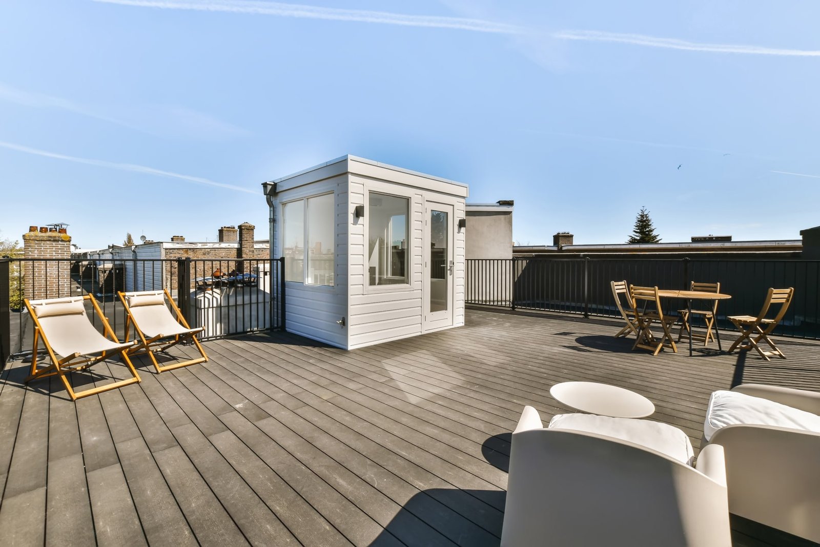 A rooftop deck with chairs and a small shed on